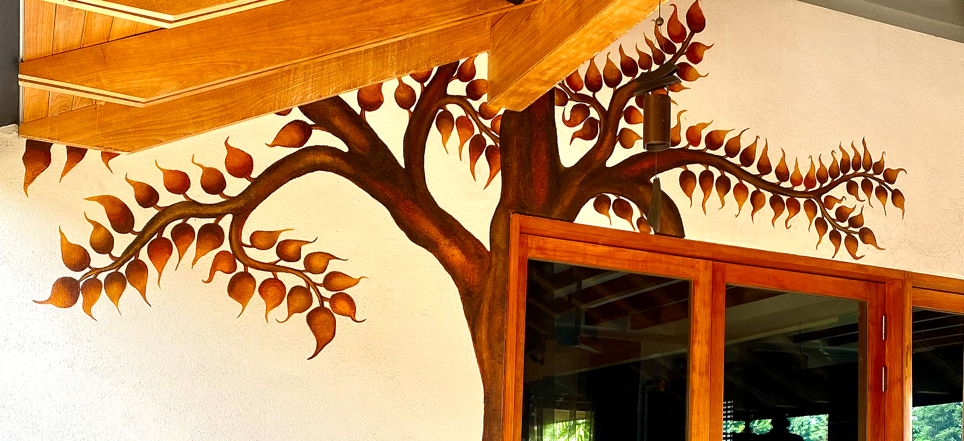 Tree mural painted across a wall and ceiling in a warm wooden interior