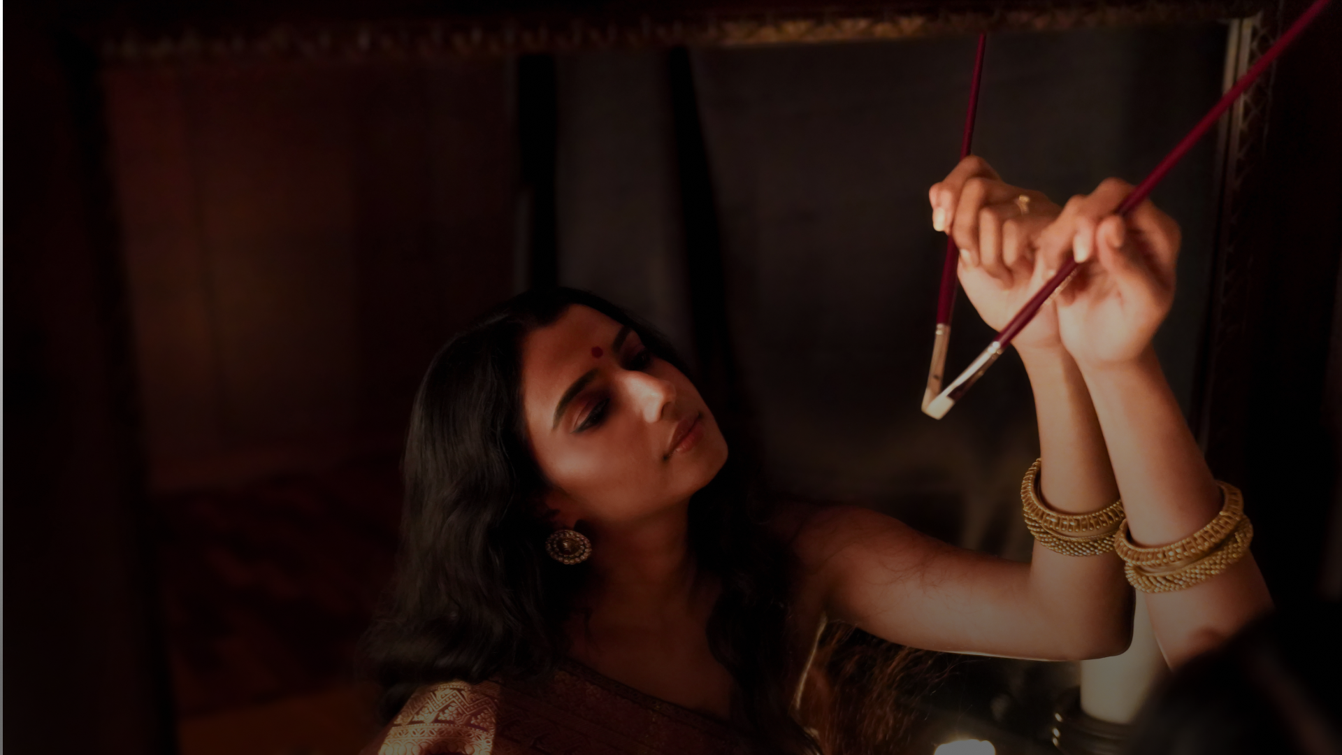 Shantrika painting in her studio, brushes raised to the canvas