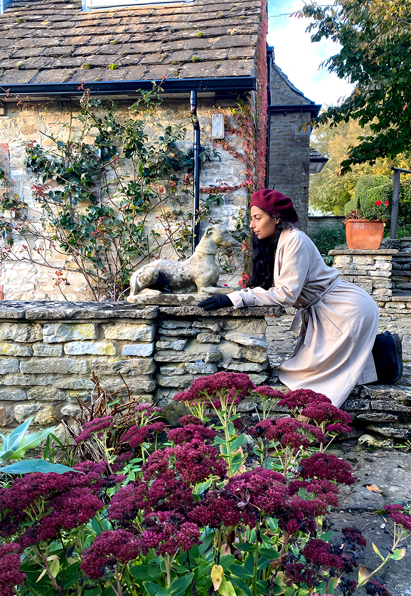 Artist beside a stone dog statue on a dry-stone wall