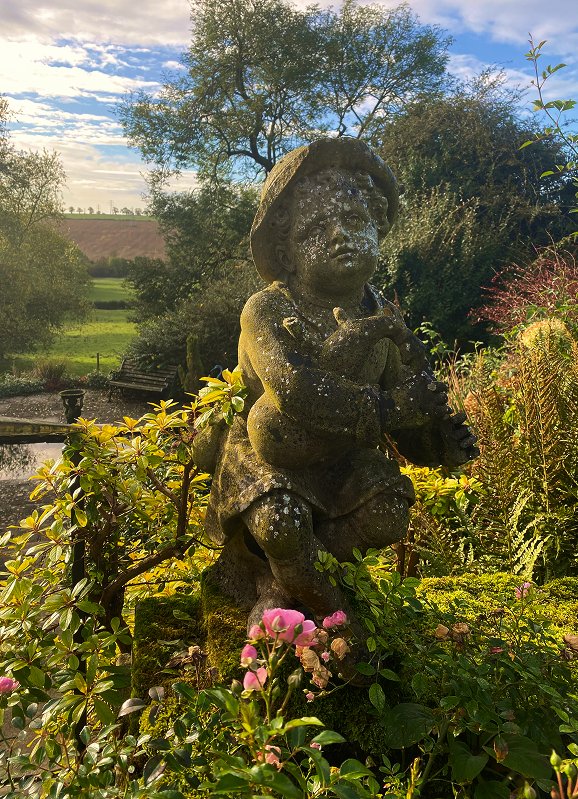 Moss-covered garden statue in evening light
